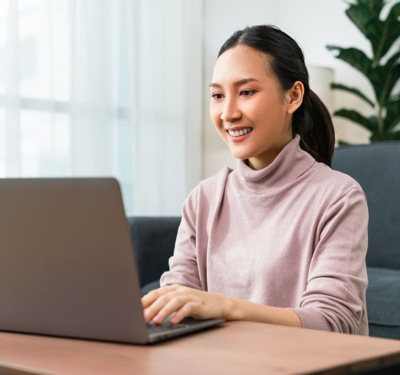 A woman is sitting at a table using a laptop computer.