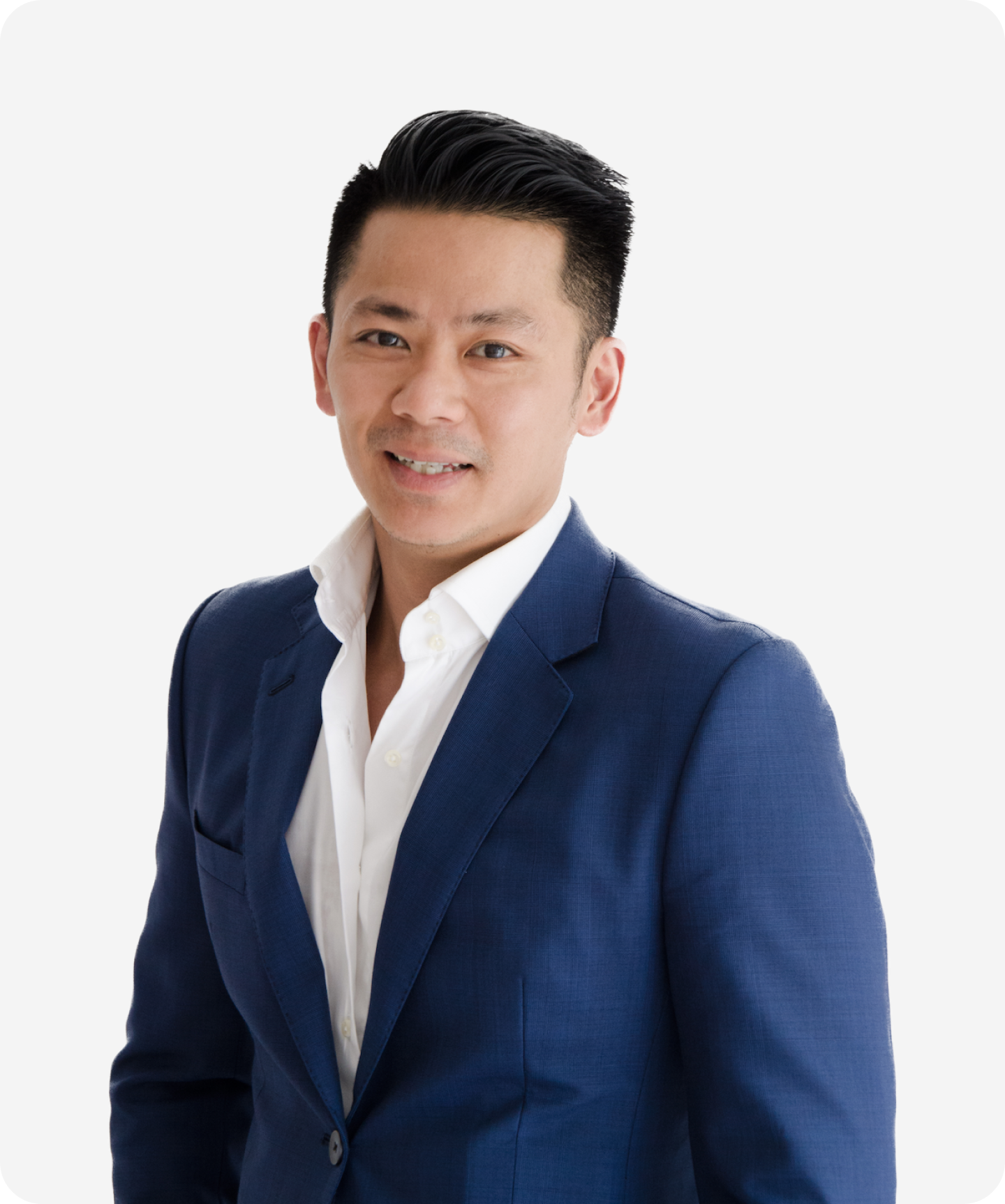 A man in a blue suit and white shirt is standing in front of a white background.