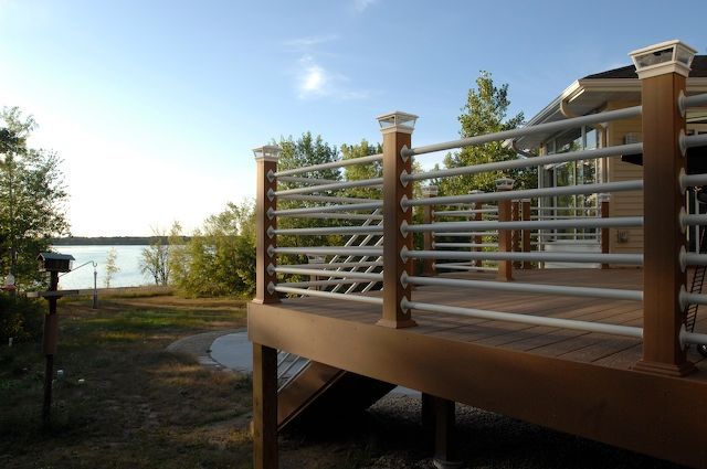 Wooden deck with metal railings overlooking a lake.