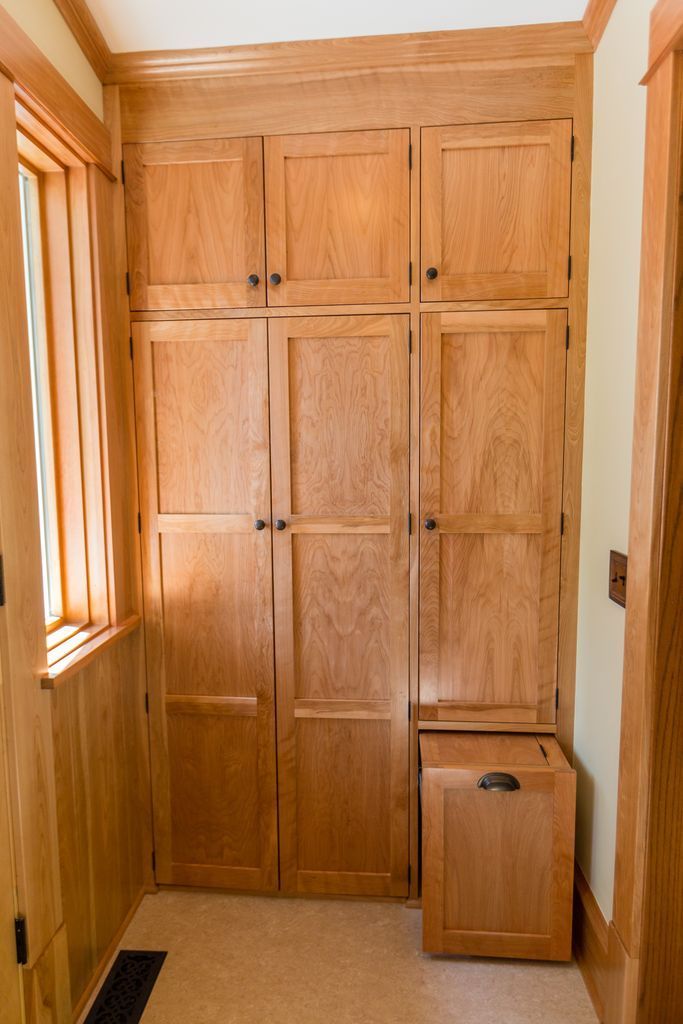 Wooden cabinets of varying sizes in a hallway; natural wood tone, built-in hamper.