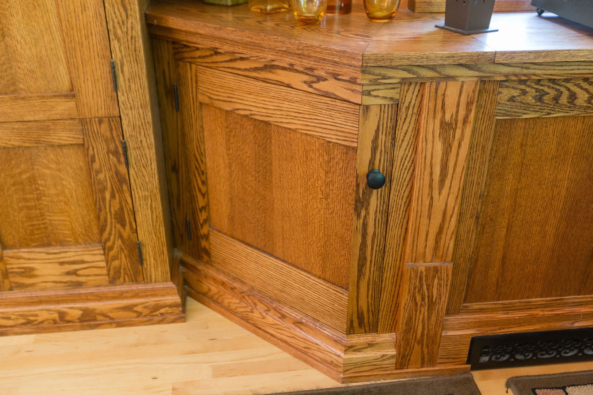Wooden cabinet with Craftsman style detailing and black hardware.