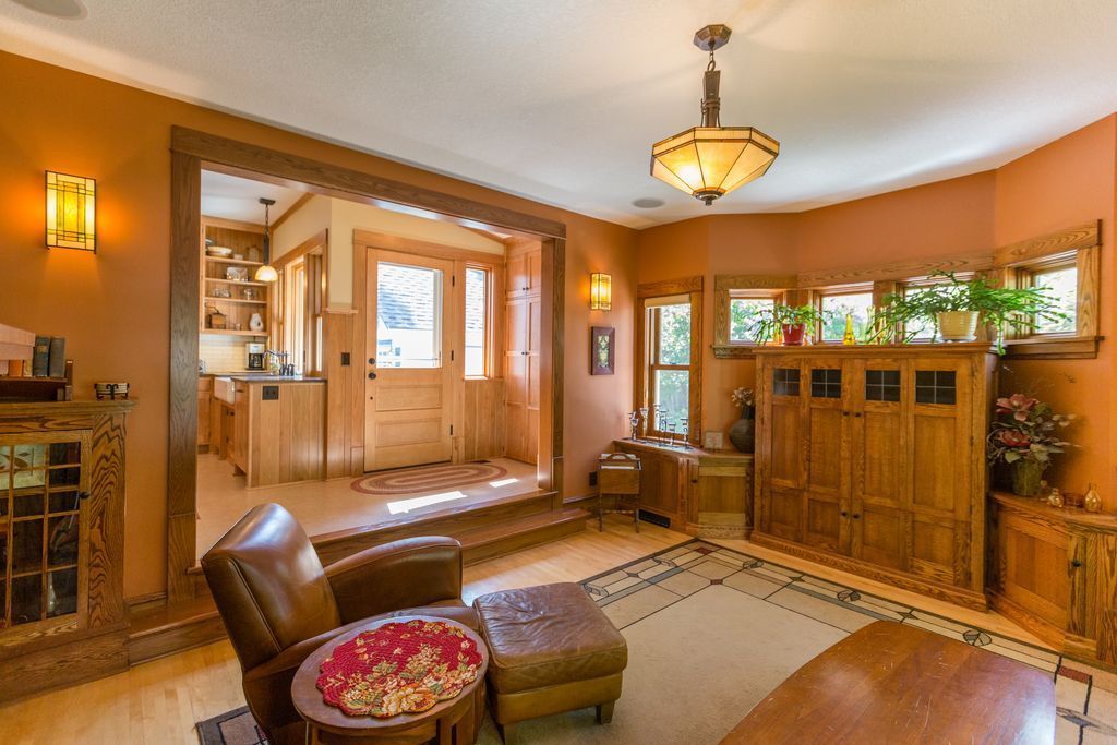 Cozy Craftsman-style living room with wood furniture, orange walls, and a view into the kitchen.
