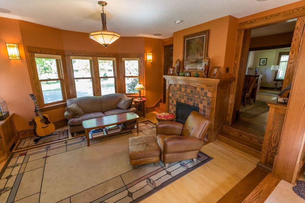 Living room with orange walls, fireplace, leather furniture, and a guitar.