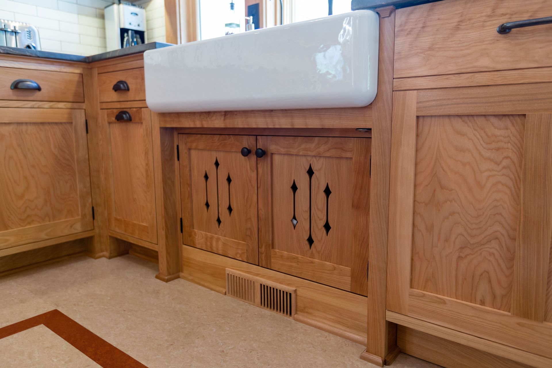 Wooden kitchen cabinets with a white farmhouse sink, decorative cabinet doors.