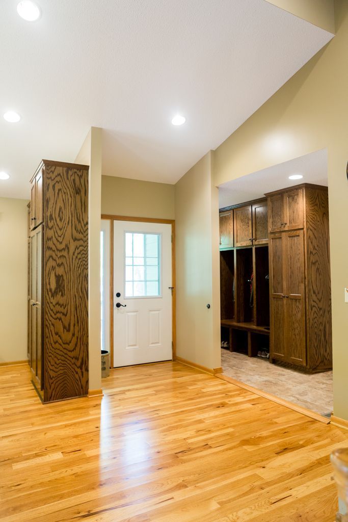 Wooden floored entryway with wood cabinetry, a white door, and built-in storage.