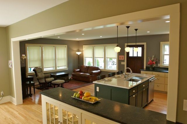 Open-concept kitchen and living room with island, sofa, windows, and doorway.