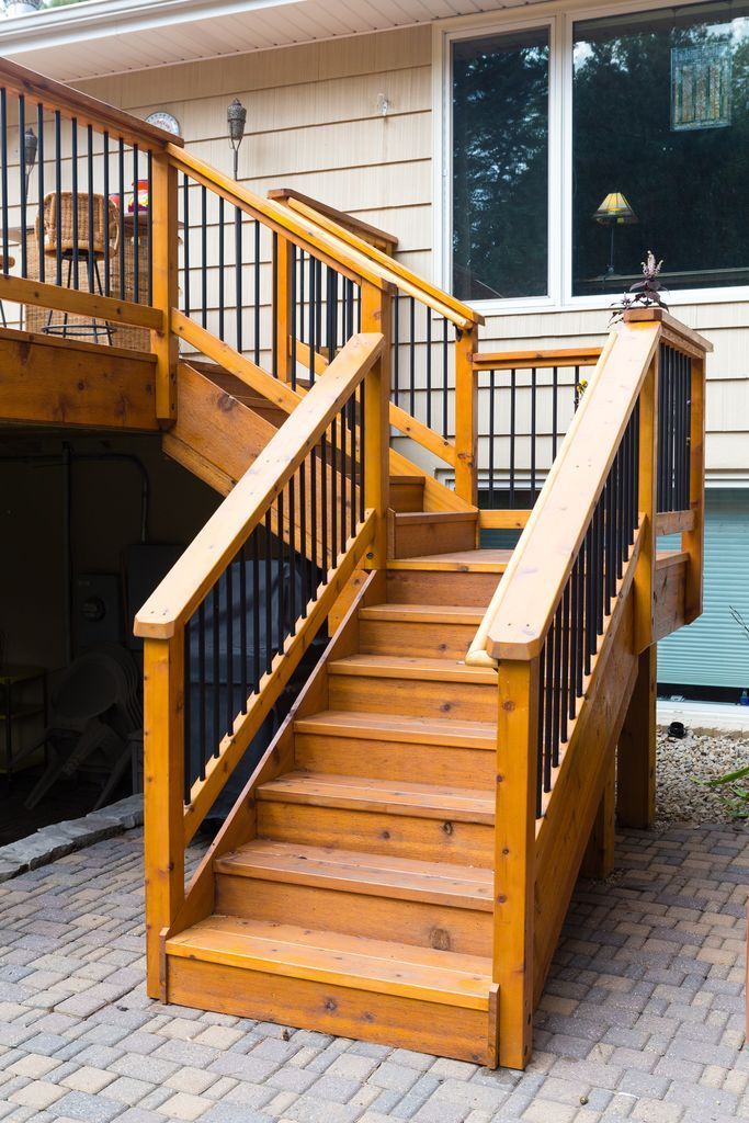 Wooden outdoor staircase with black railings and a landing.