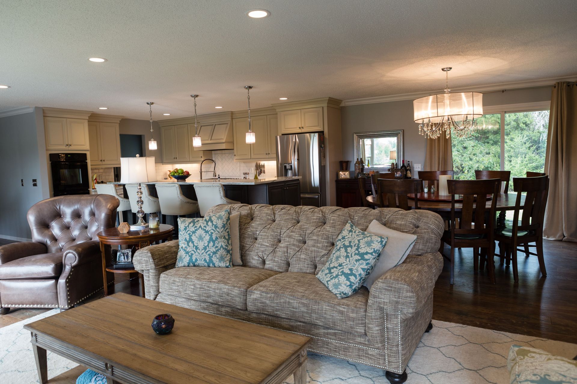 Open-concept living space with a kitchen island with barstools, living area with a TV, and hardwood floors.