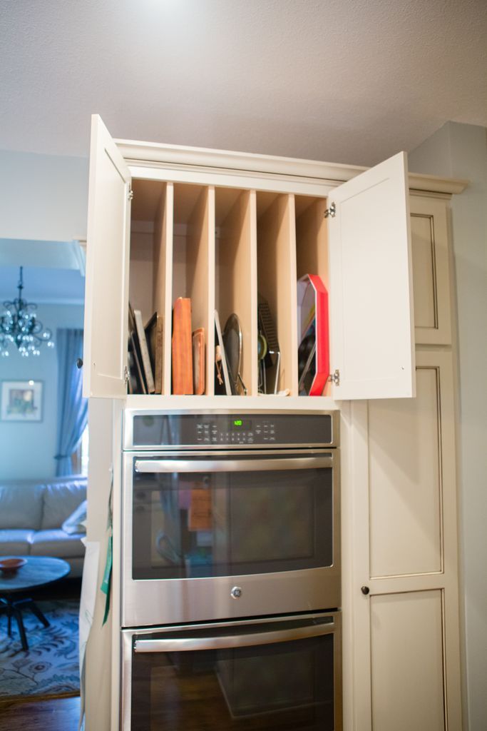 Cabinets above double oven with vertical dividers holding baking sheets, pans, and other kitchen items.