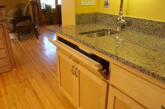 Kitchen with light wood cabinets, granite countertop, and a pull-out tray.