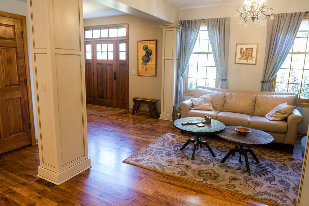 Living room with leather sofa, two round coffee tables, patterned rug, and wooden door.