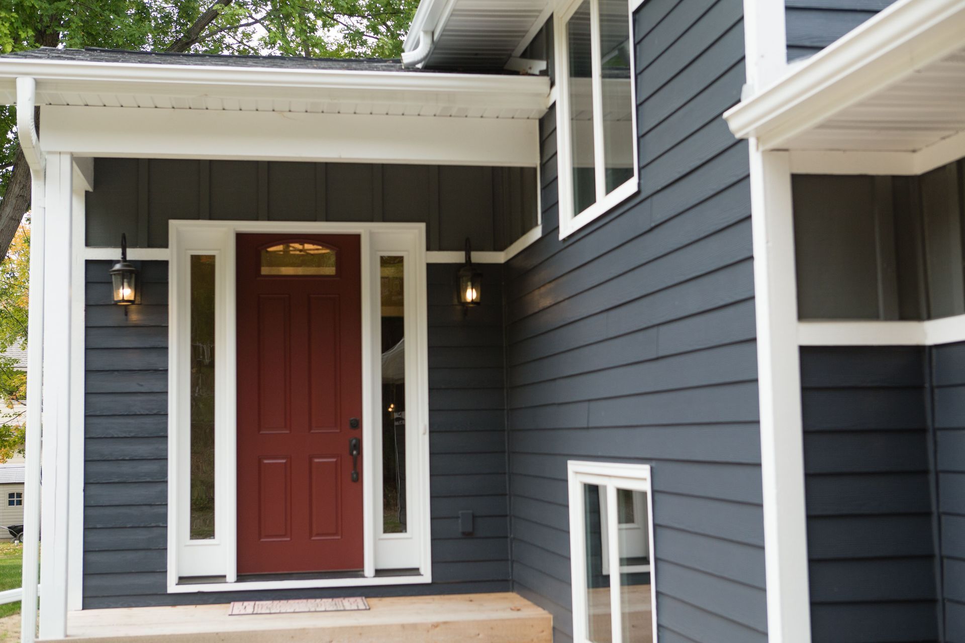 Dark gray house exterior with a red front door and white trim.