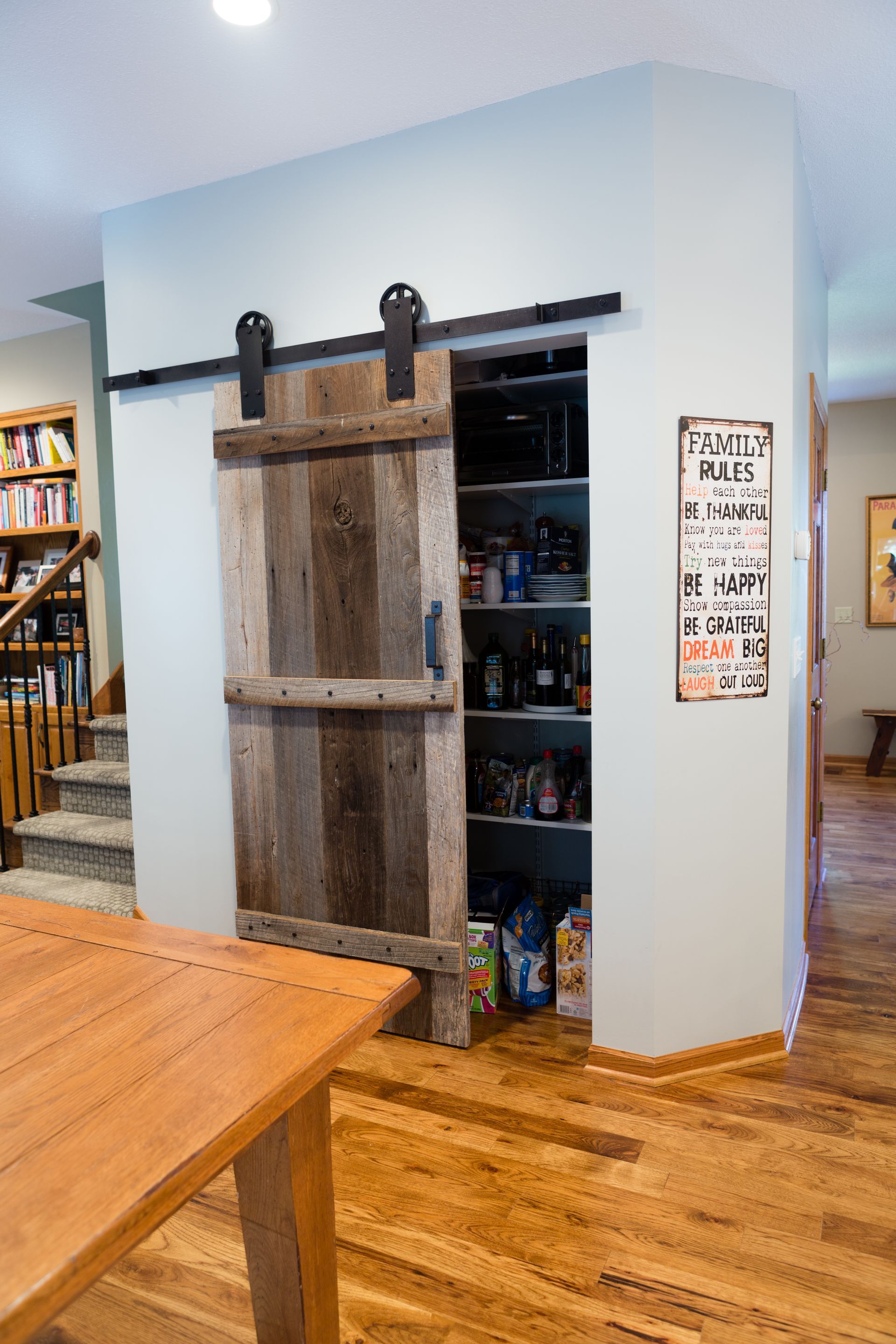 Barn door pantry with shelves. Wood floor, light blue wall.