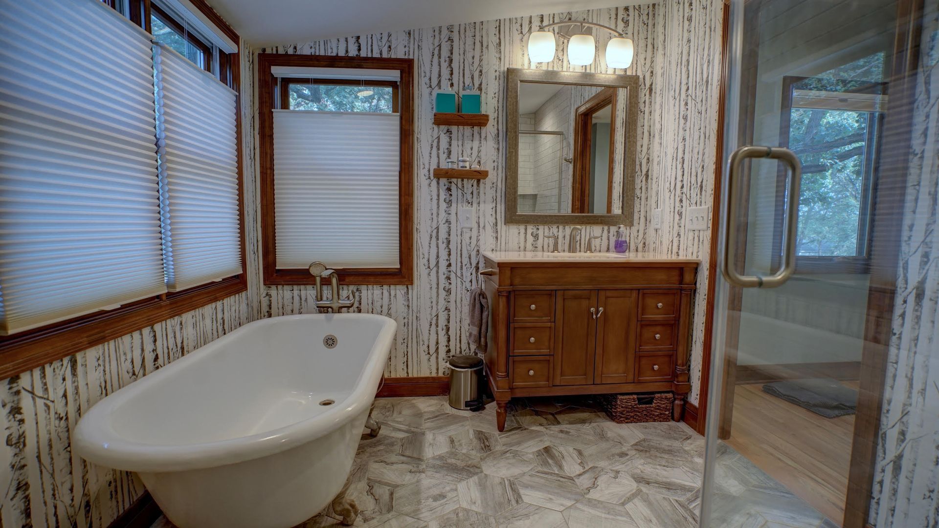 Bathroom with a white tub, wooden vanity, and textured wallpaper.