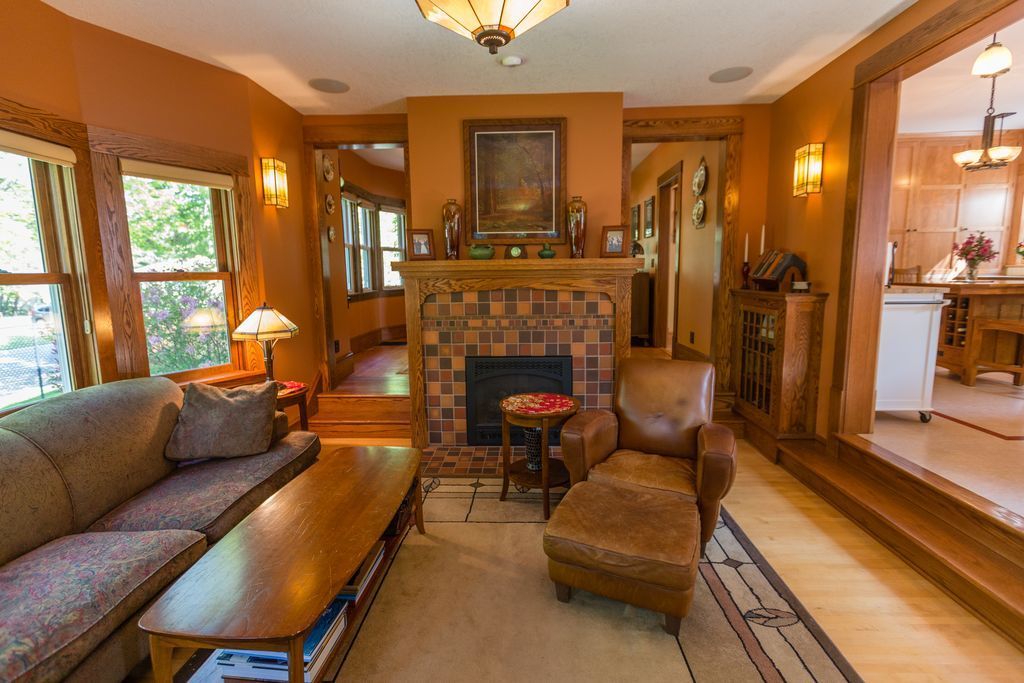 Cozy living room with brown walls, fireplace, sofa, armchair, and doorway to kitchen.