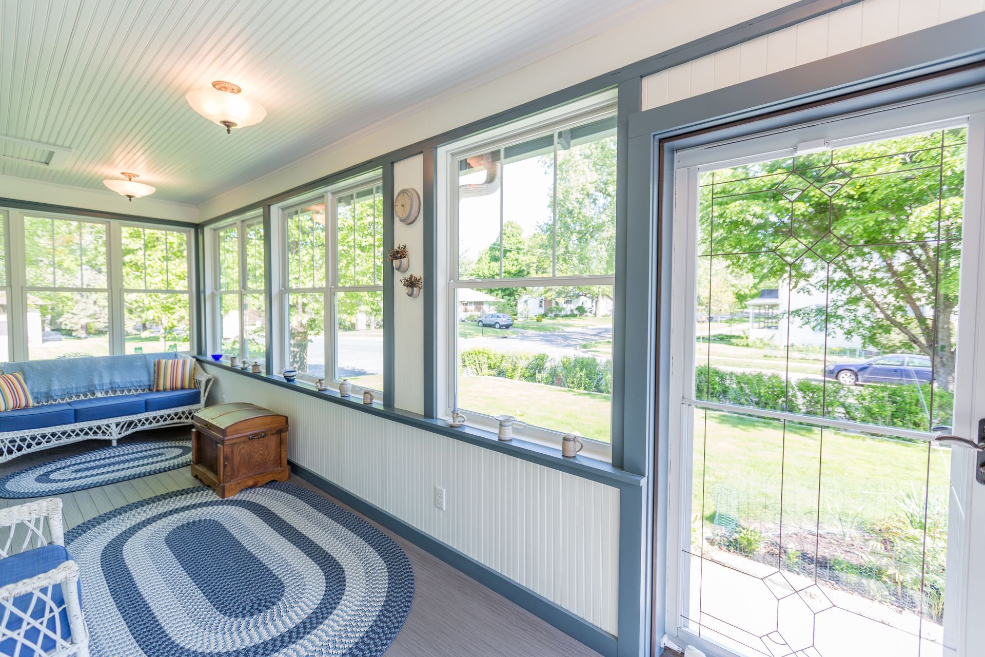 Sunroom with blue and white decor, windows, and a door to a yard.