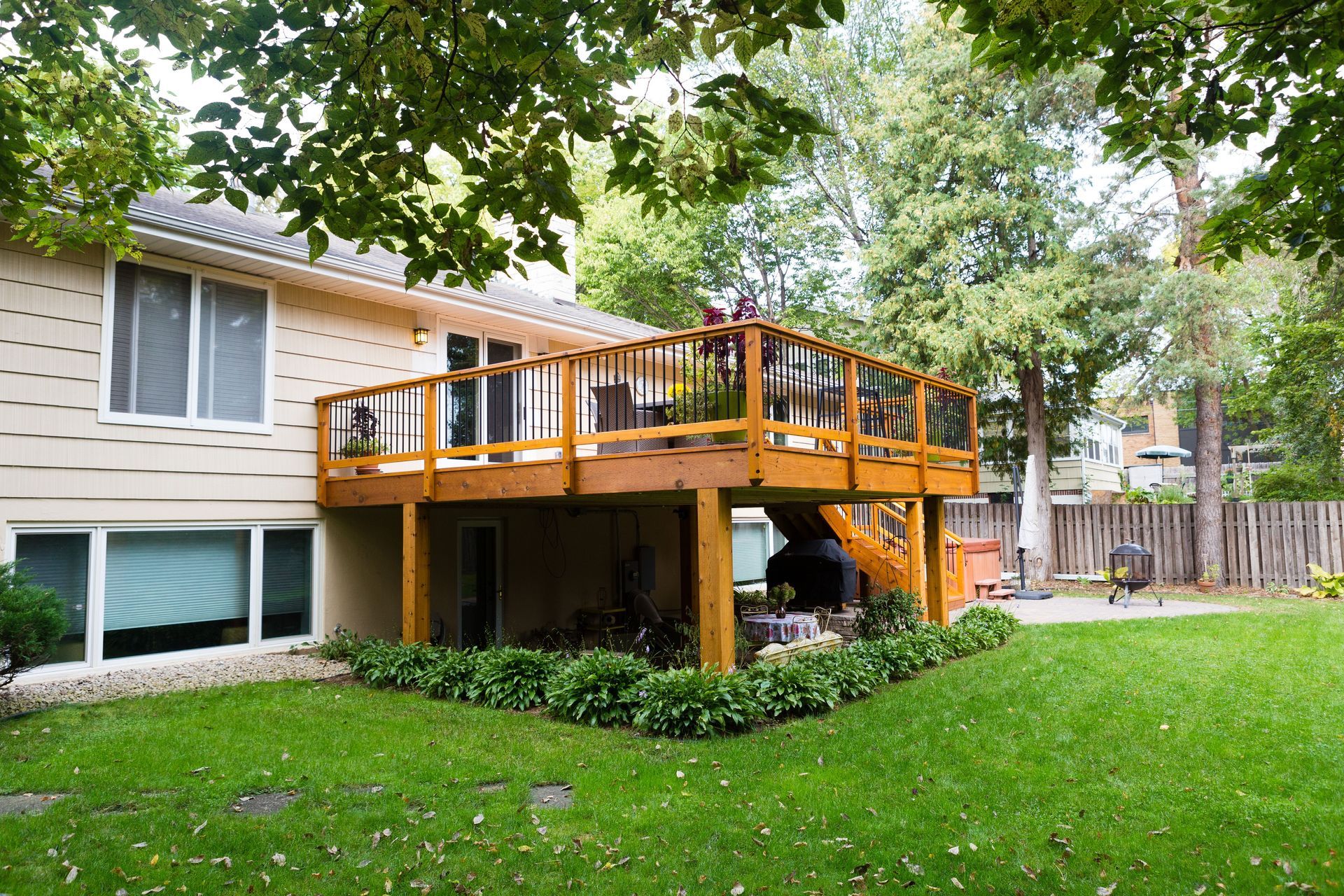 A two-story house with a wooden deck and a green yard.