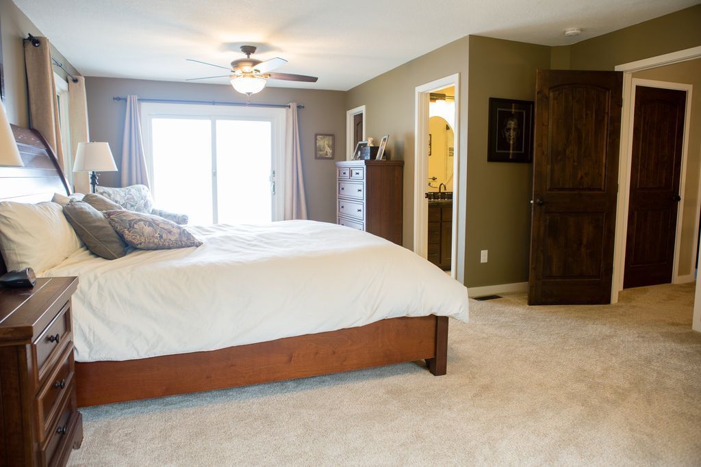 Spacious bedroom with a king-sized bed, sliding door, and access to a bathroom and closet.