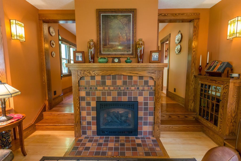 Living room with fireplace, orange walls, wooden accents, artwork, and radiator.