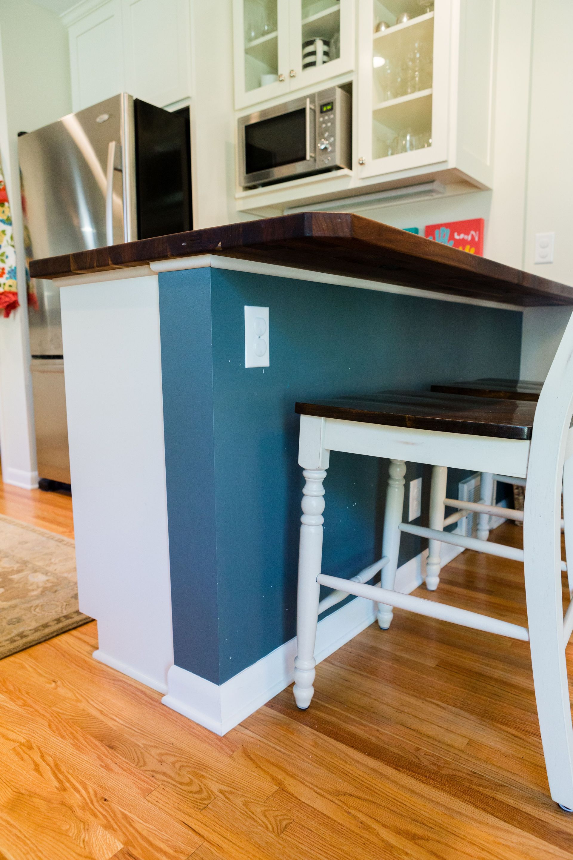 Kitchen island with dark wood countertop, blue and white paint, and a small table.