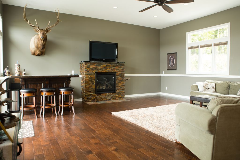 Living room with fireplace, mounted elk head, bar, and wooden floor.