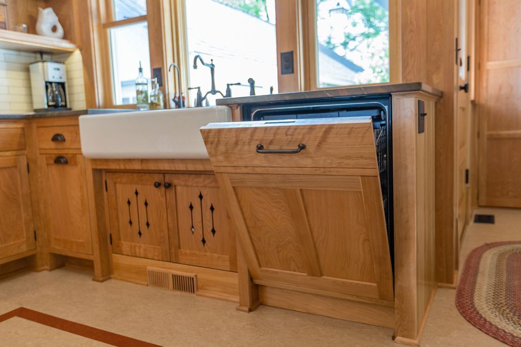 Wooden kitchen with a dishwasher, sink, and cabinets. The dishwasher door is open.
