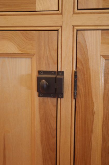 Wooden cabinet doors with a dark metal latch and hinge.