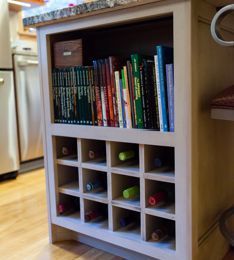 Kitchen island with bookcase and wine rack; books, bottles, and wood box visible.