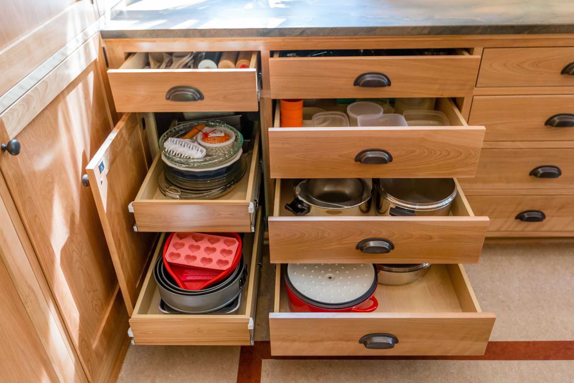 Wooden kitchen drawers open, displaying cookware.