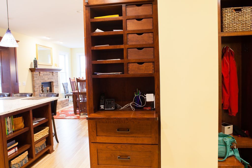 Wooden storage unit with drawers and shelves, separating kitchen from hallway.