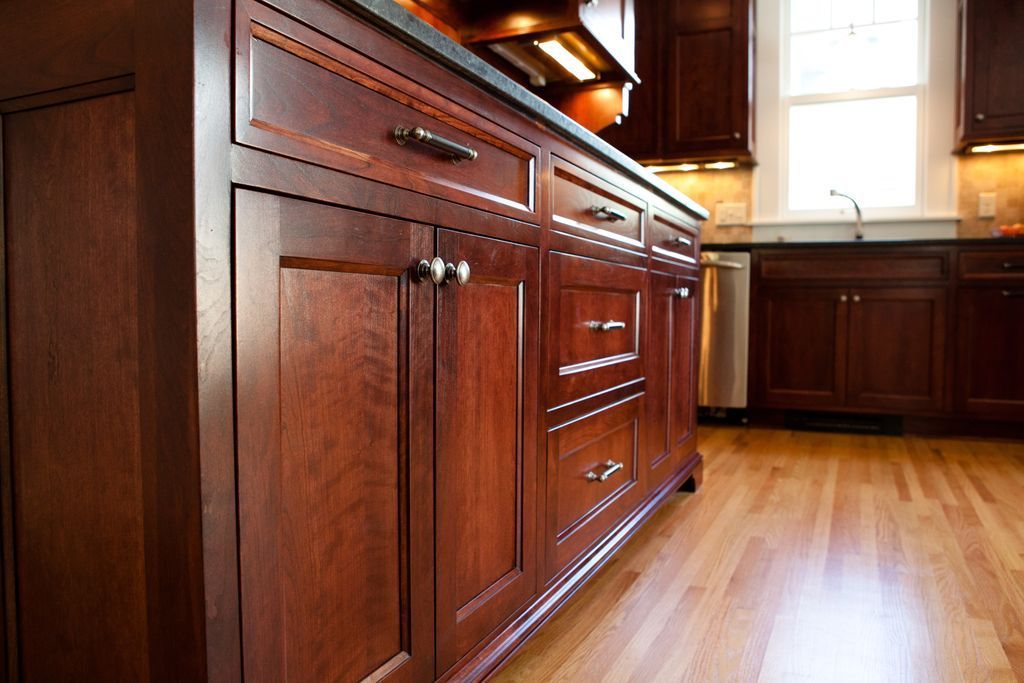 Kitchen island with dark wood cabinets, drawers, and a countertop; hardwood floors.