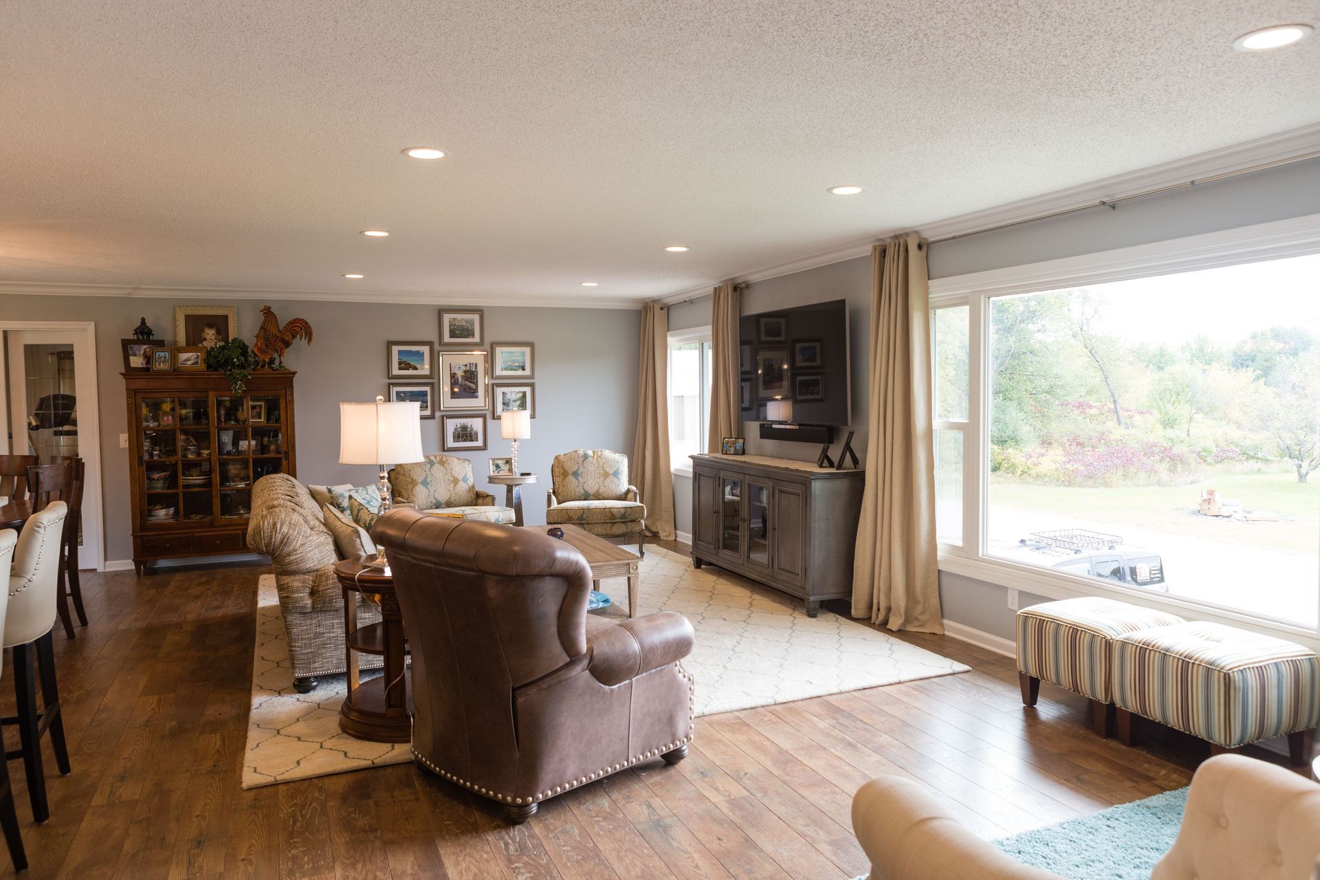 Spacious living room with brown leather armchair, gray walls, and a large window with a view.