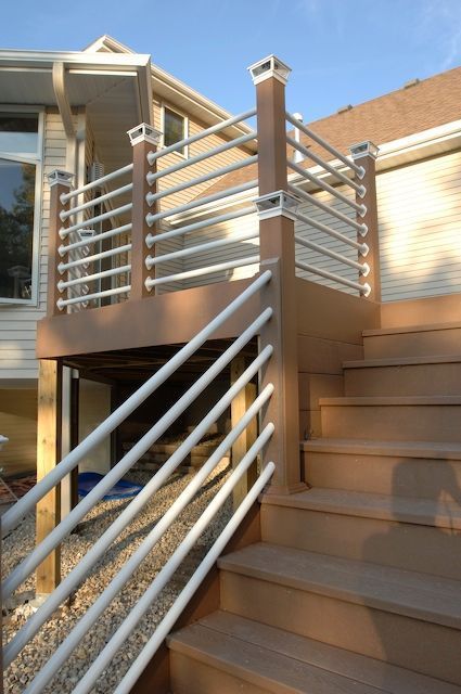 Deck with brown steps, brown and white railing, and house in background.