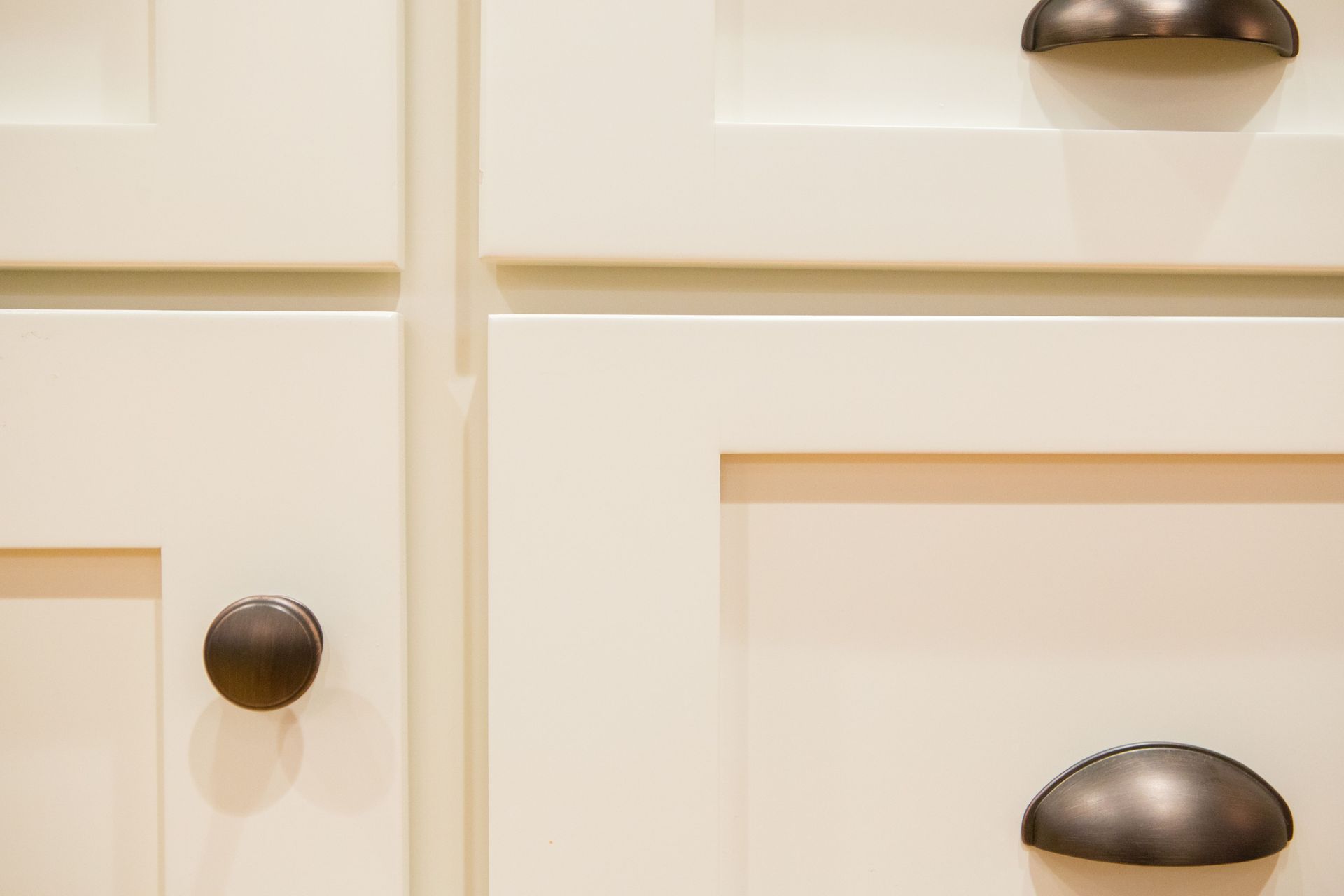 Cream-colored cabinet doors with recessed panels and bronze-toned knobs.