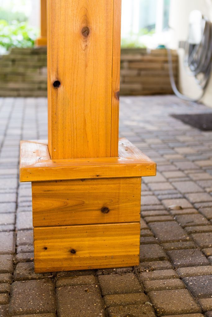 Wooden pillar with a square base on a brick patio.