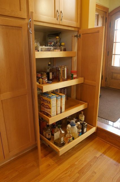 A pantry with pull-out shelves filled with food items, set in a kitchen.