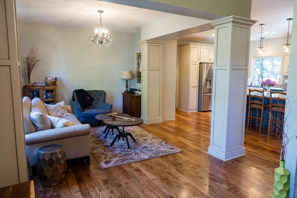 Living room with hardwood floors, connected to a kitchen. A couch, chairs, and table are present.