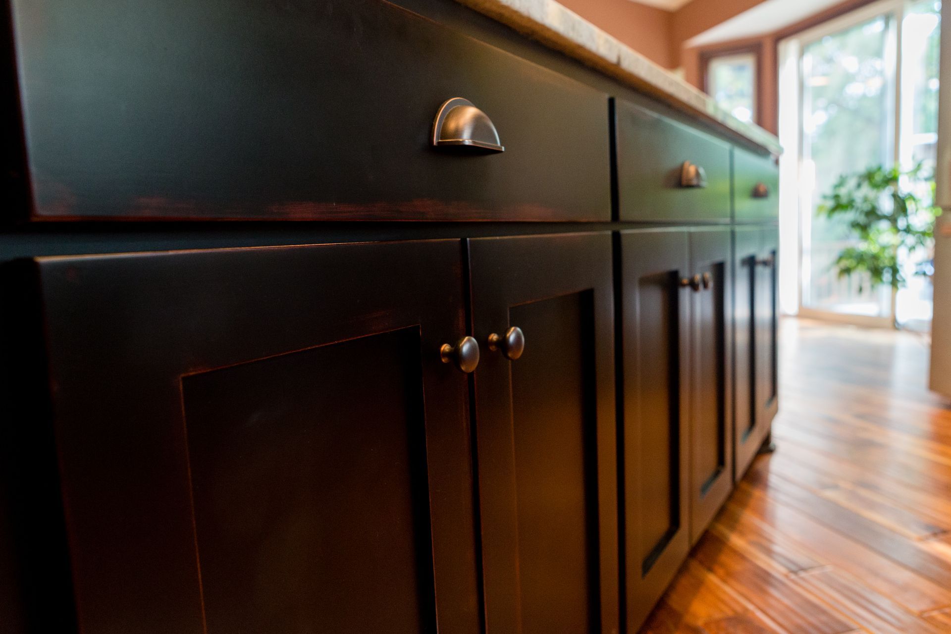Black kitchen cabinets with silver hardware and a marble countertop.