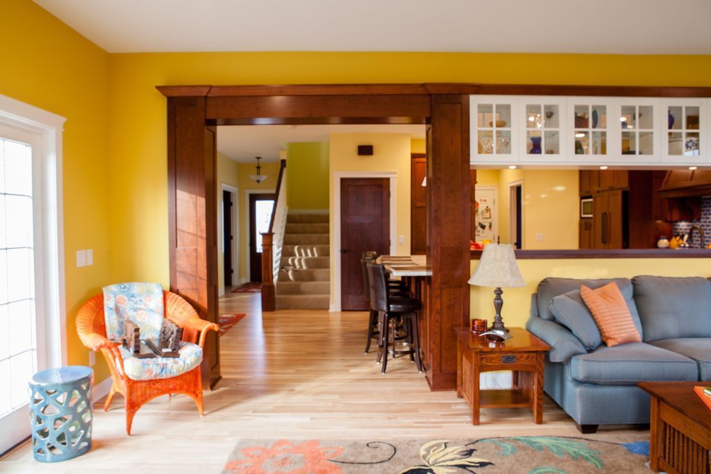 Living room with yellow walls, hardwood floors, brown trim, and blue sofa.