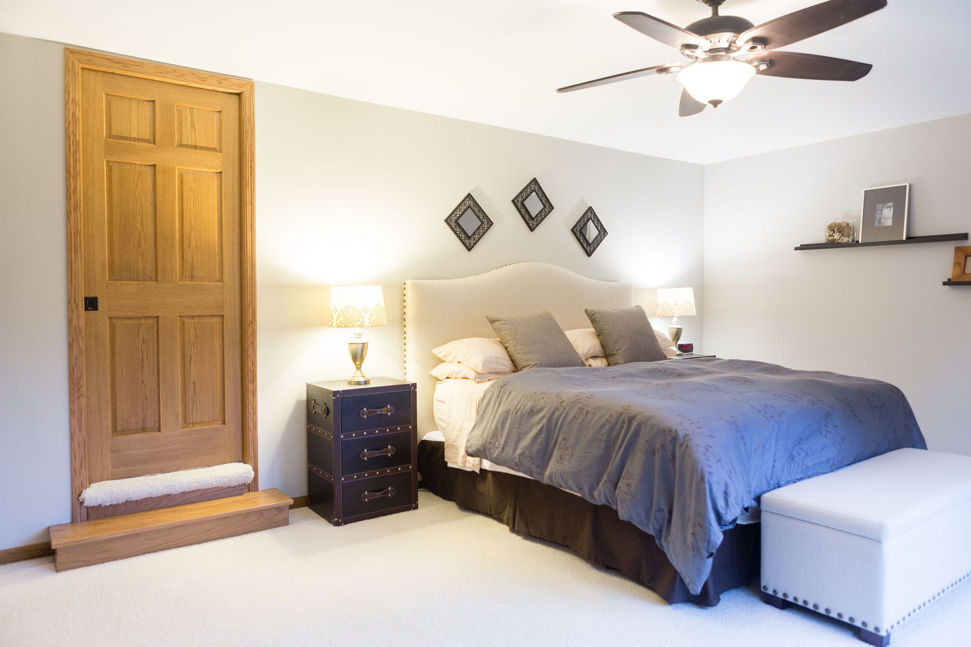 Bedroom with bed, nightstand, door, and decorative wall art.
