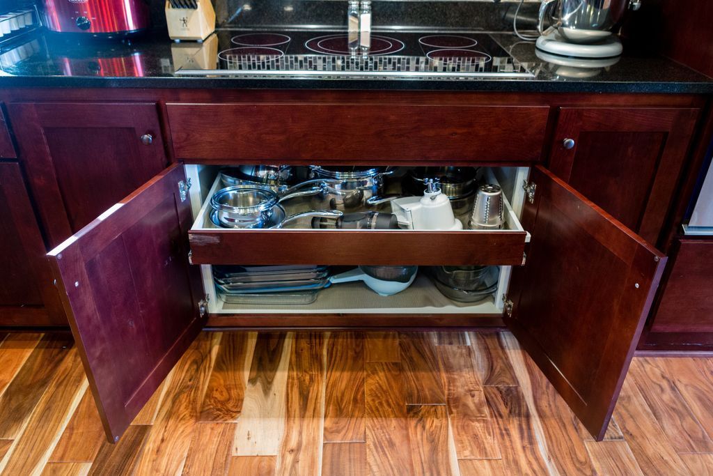 Kitchen cabinet open, revealing glassware and baking dishes on pull-out shelves.