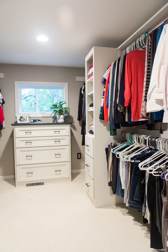 Walk-in closet with white cabinetry, hanging clothes, a chest of drawers, and a window.