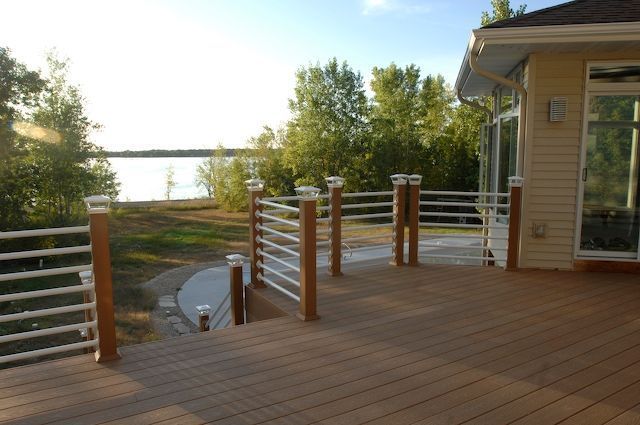 Deck with brown composite and white railing overlooking a lake.