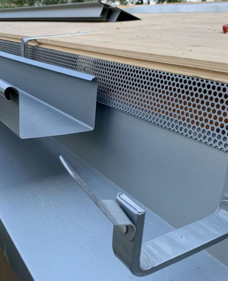 Gray metal gutter system in north little rock with perforated screen and wooden edge.