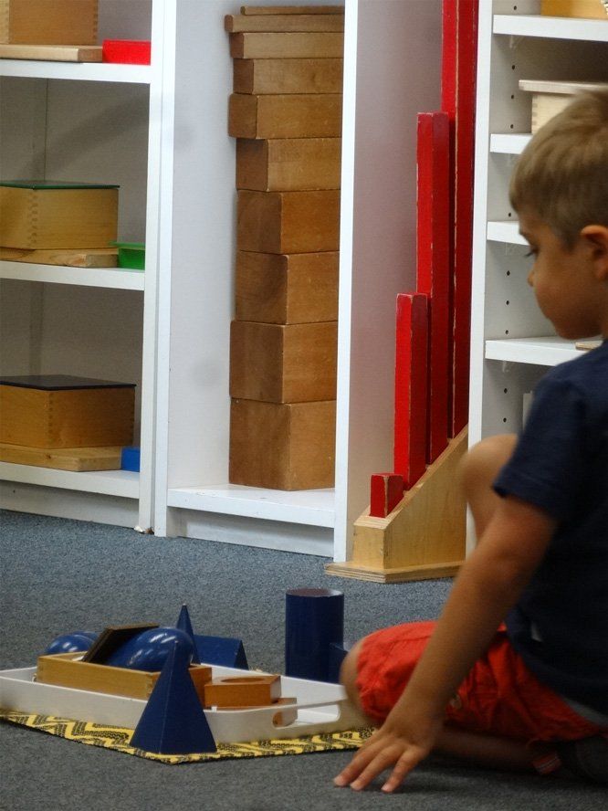Boy Puzzle — Little Boy in Blue Shirt Inside Montessori Looking in a Puzzle in North Bend, WA