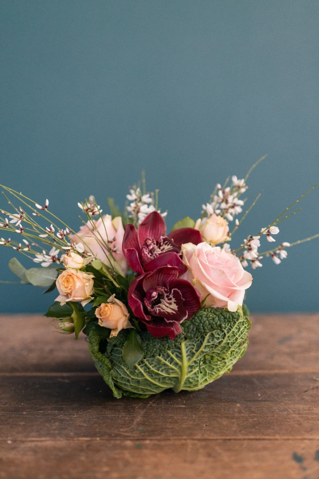 un bouquet di fiori è seduto in un cavolo su un tavolo di legno .