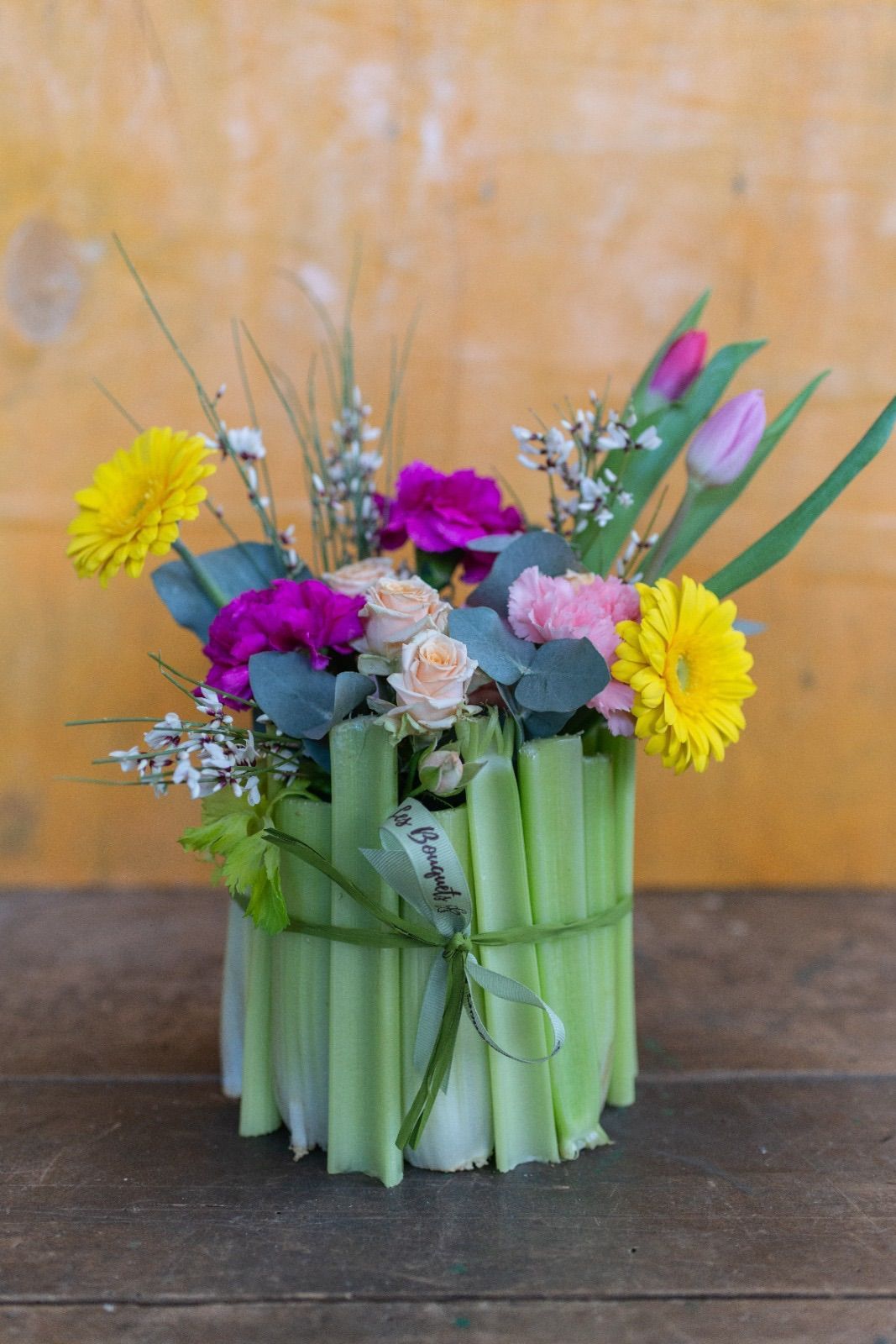 un vaso pieno di fiori è seduto su un tavolo di legno .