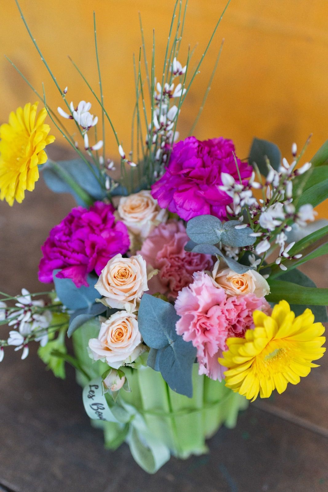 un vaso pieno di fiori colorati è seduto su un tavolo di legno .