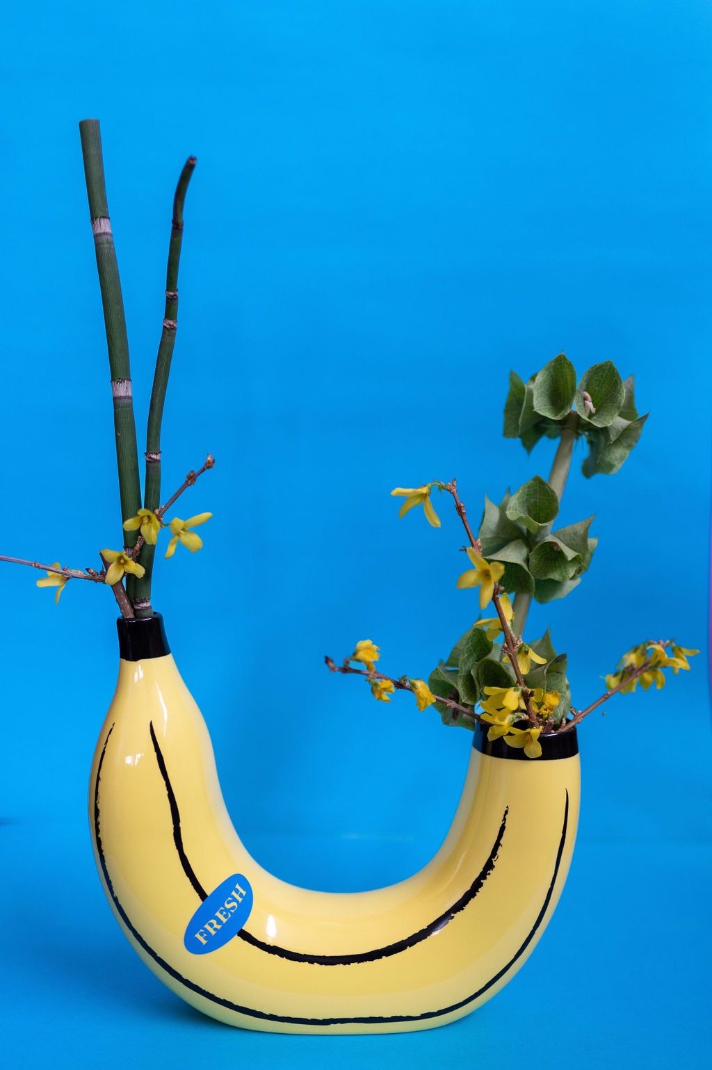 un vaso a forma di banana pieno di fiori su sfondo blu