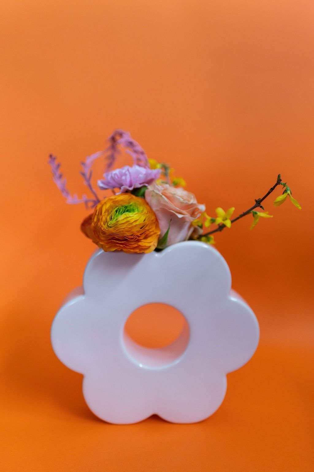 un vaso bianco con fiori su sfondo arancione .
